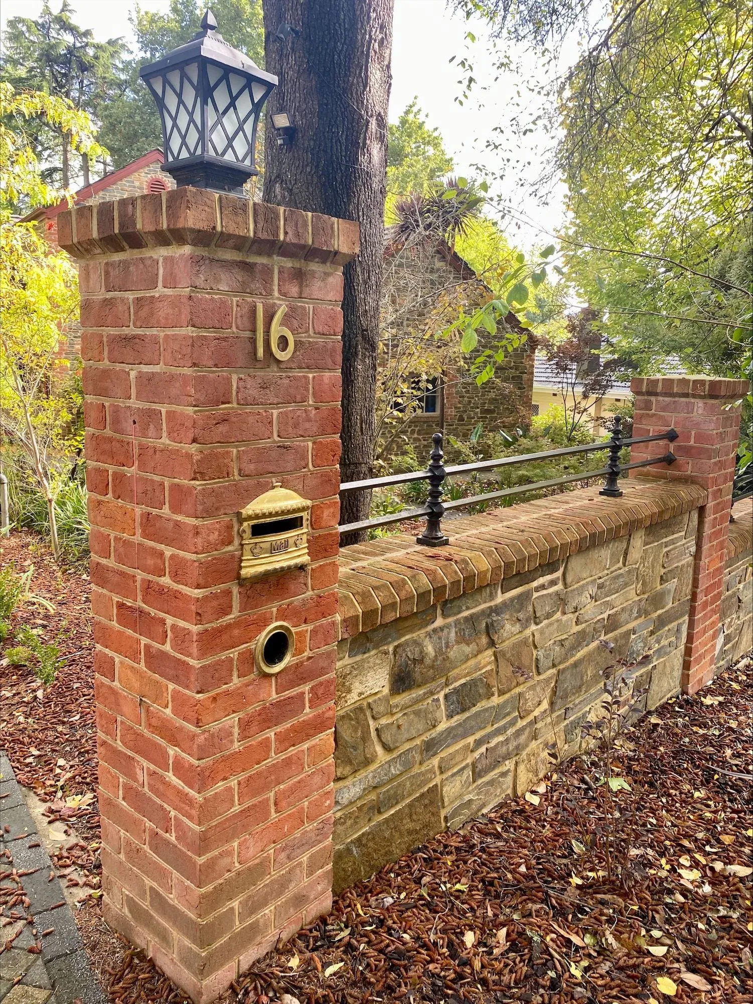 A red brick pier and stone-and-brick front wall with a house number