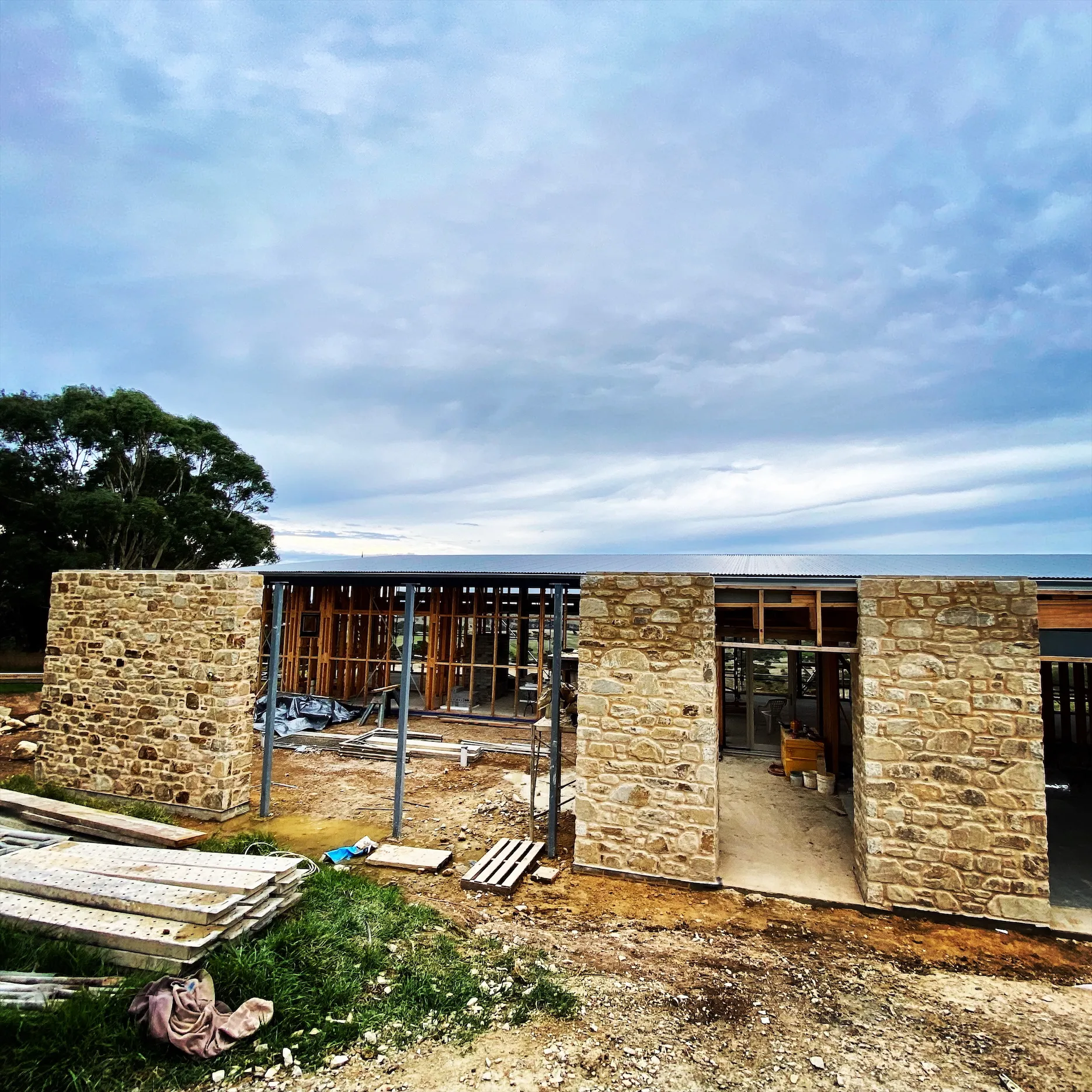 Stone walls going up around a timber frame on a coastal site