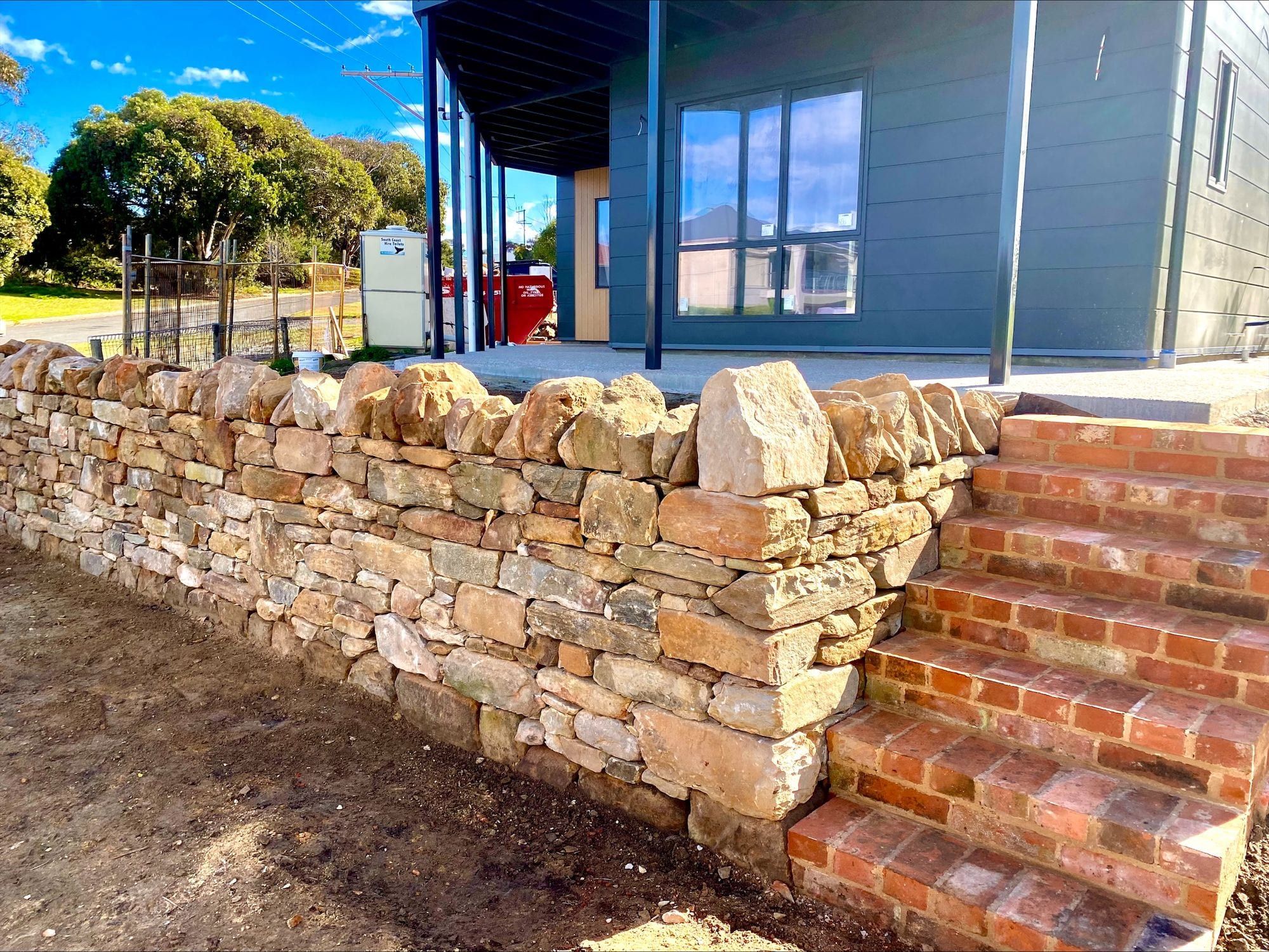 A dry stone wall and brick steps on a sloping garden