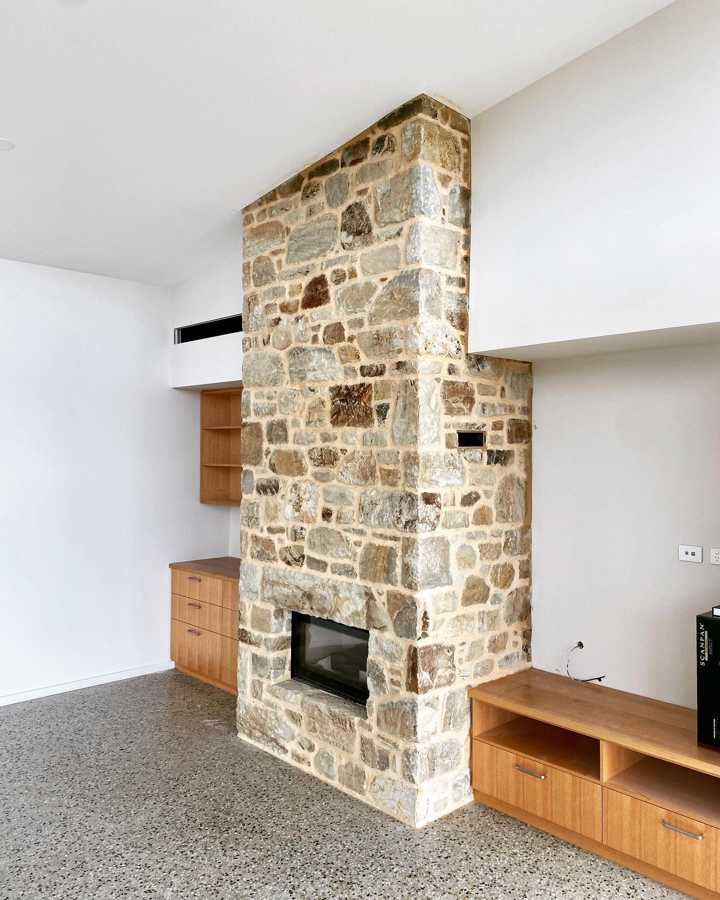 A floor-to-ceiling stone fireplace chimney in a bright modern living room