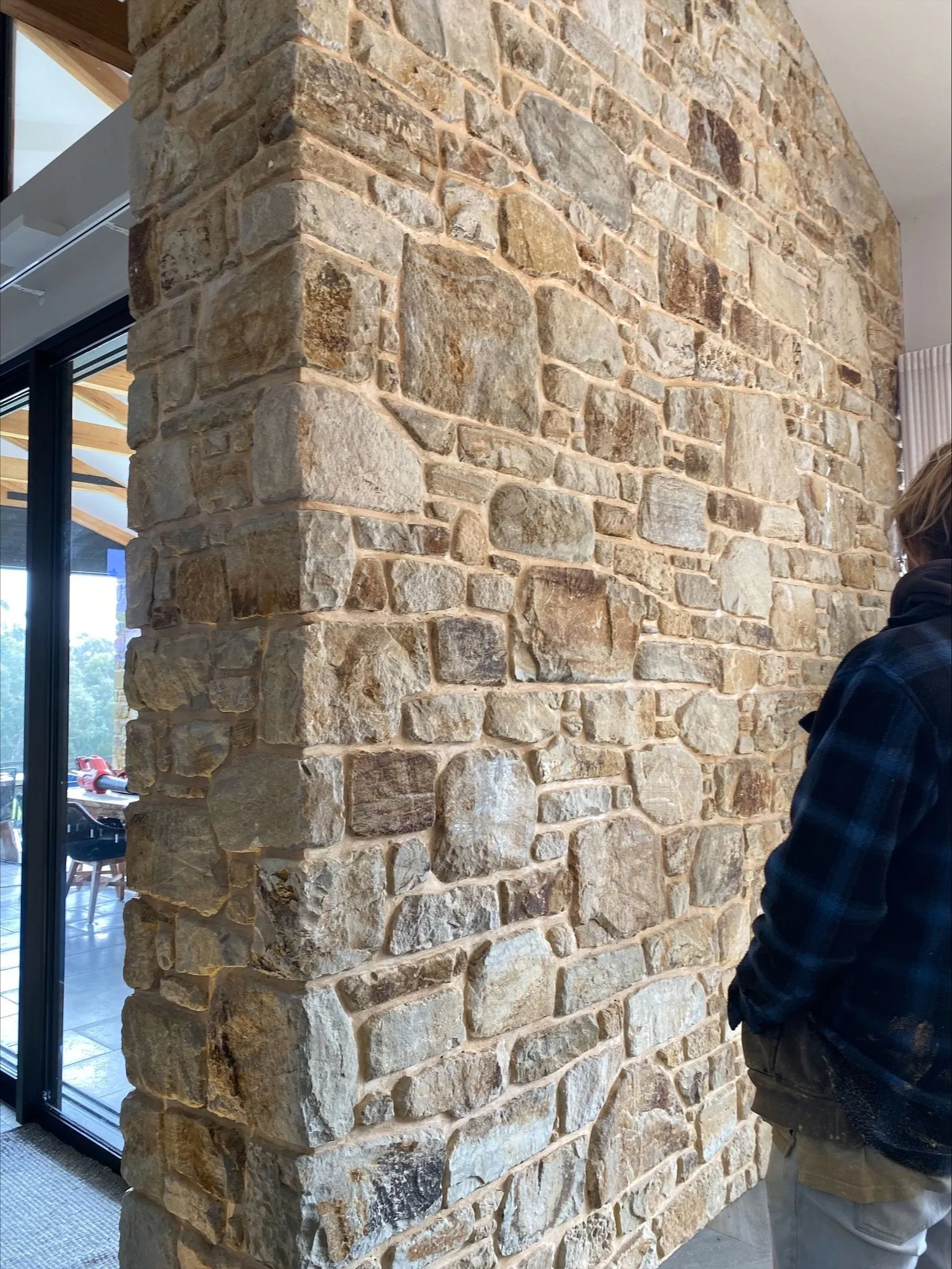 A tall stone column beside a glass wall