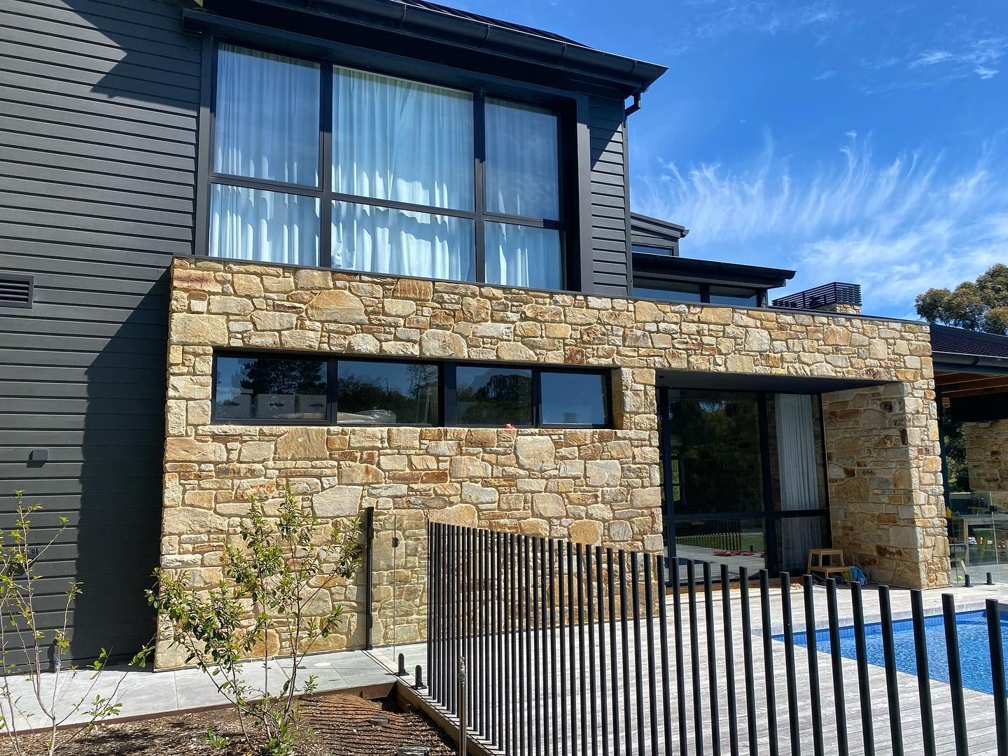 A stone-fronted modern two-storey home beside a pool